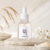 Beauty of Joseon Glow Deep Serum Rice + Alpha-Arbutin présenté sur un socle clair avec grains et épis de riz.