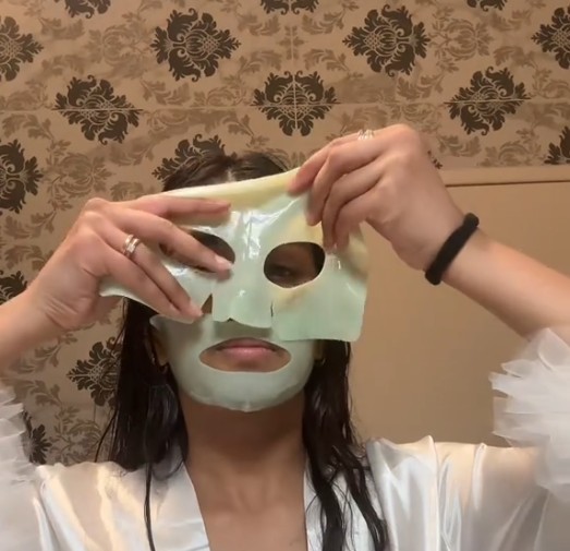 Femme appliquant la partie supérieure du masque Anua Heartleaf 70 + Hyaluron sur son visage, la partie inférieure déjà en place.