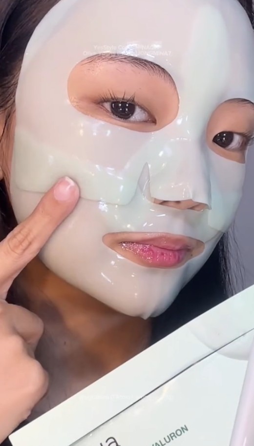 Gros plan d’une femme portant l’Anua Heartleaf 70 + Hyaluron Soothing Collagen Mask et montrant la texture du masque sur sa joue.