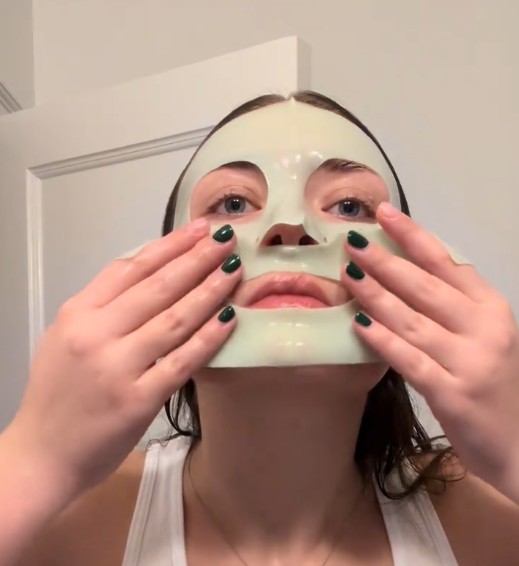 Femme ajustant l’Anua Heartleaf 70 + Hyaluron Soothing Collagen Mask autour de la bouche et du menton.