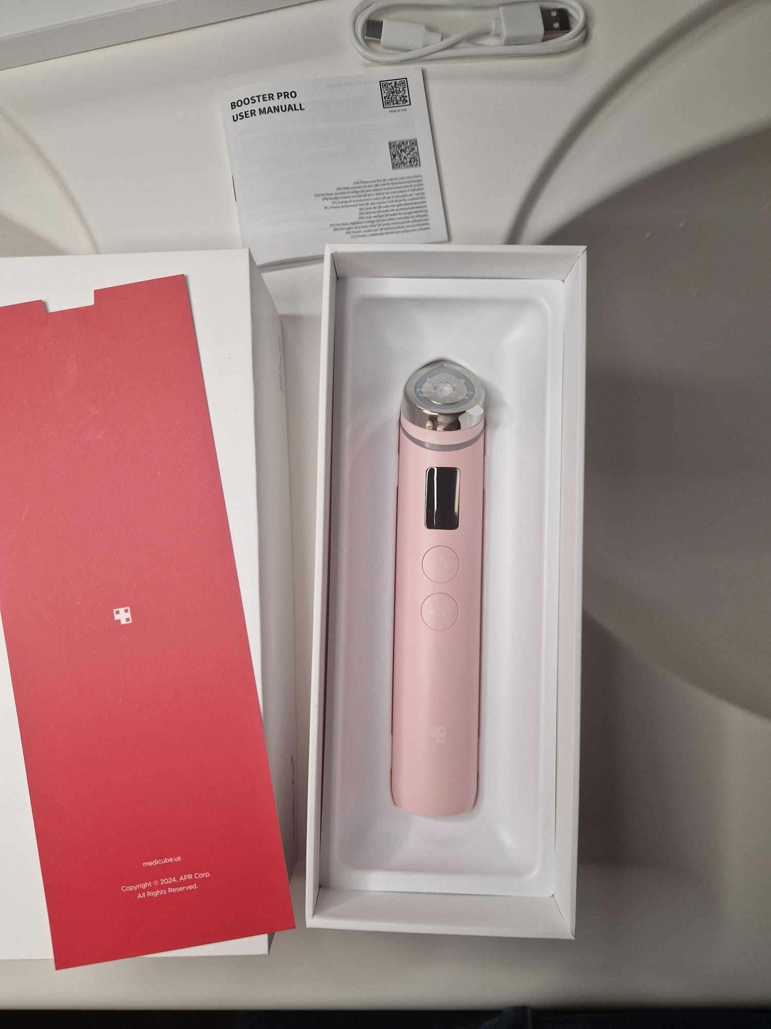 Medicube AGE-R Booster Pro Pink Edition dans son coffret ouvert avec sa boîte et ses accessoires.