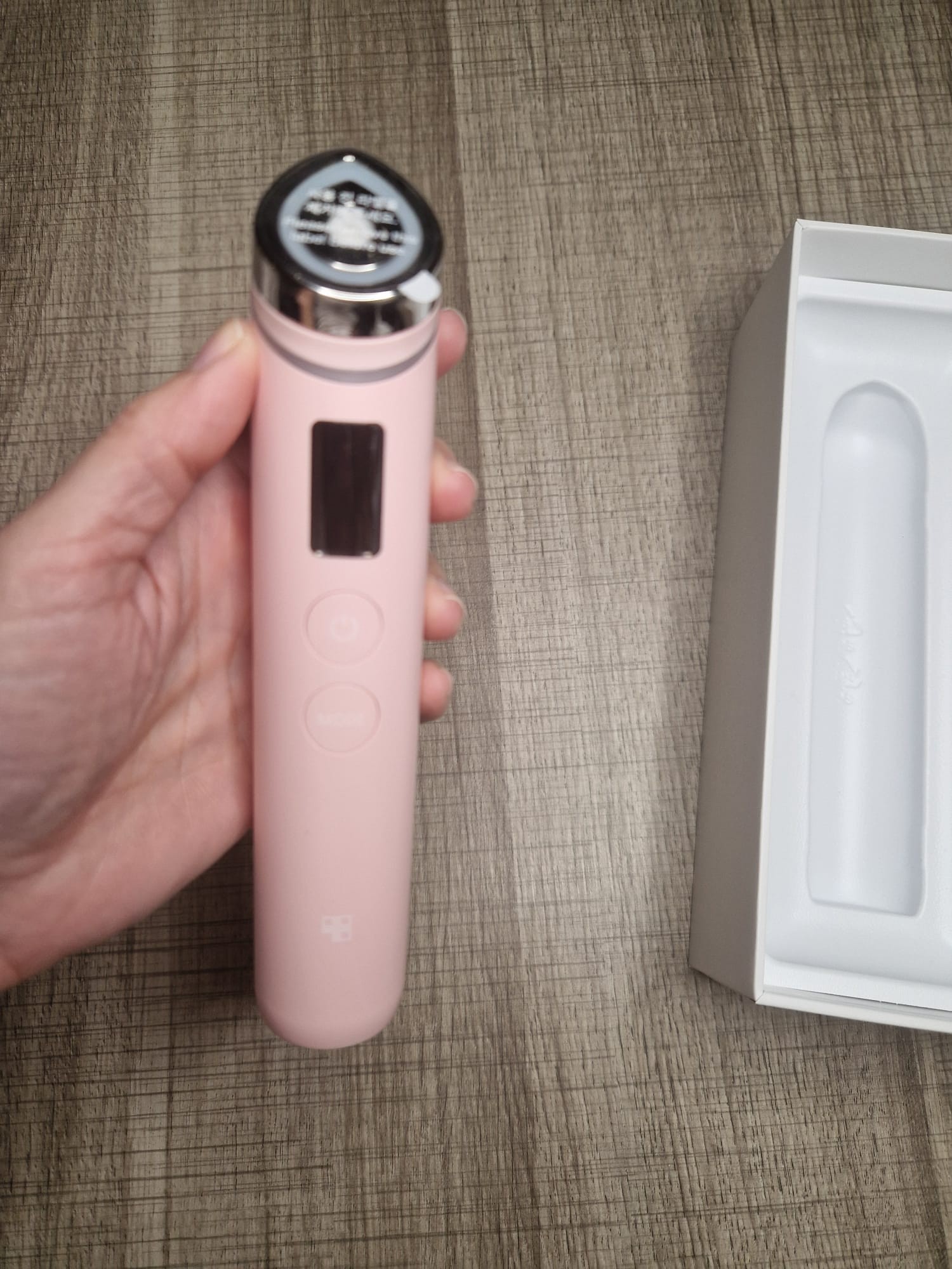 Medicube AGE-R Booster Pro Pink Edition tenu en main à côté de son coffret ouvert.