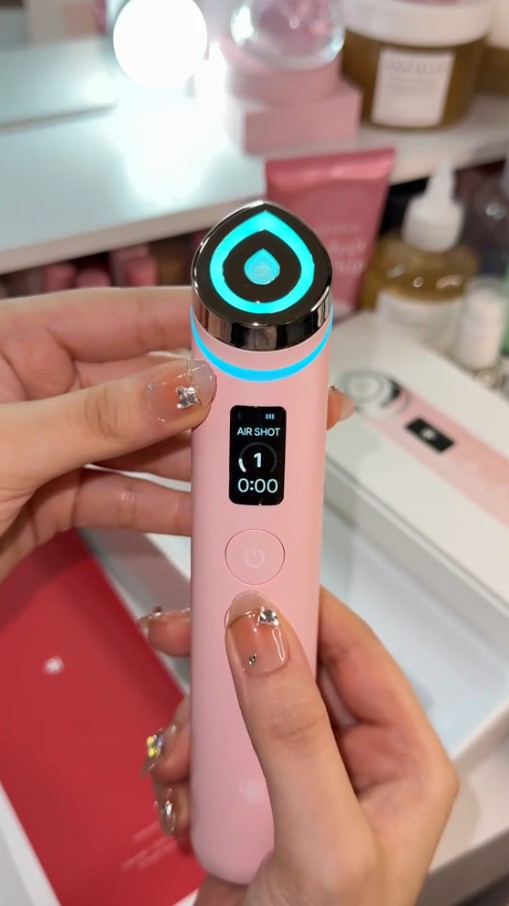 Medicube AGE-R Booster Pro Pink Edition allumé en mode Air Shot avec éclairage bleu autour de la tête de soin.
