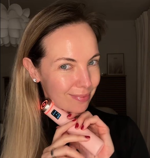 Femme utilisant le Medicube AGE-R Booster Pro Pink Edition le long de la mâchoire dans sa routine de soin.