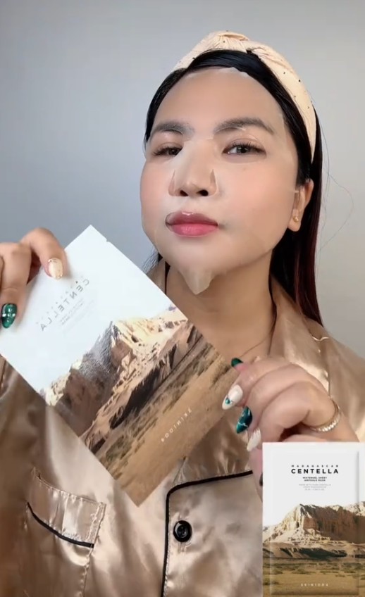 Femme présentant le sachet SKIN1004 Madagascar Centella Watergel Sheet Ampoule Mask avant utilisation.