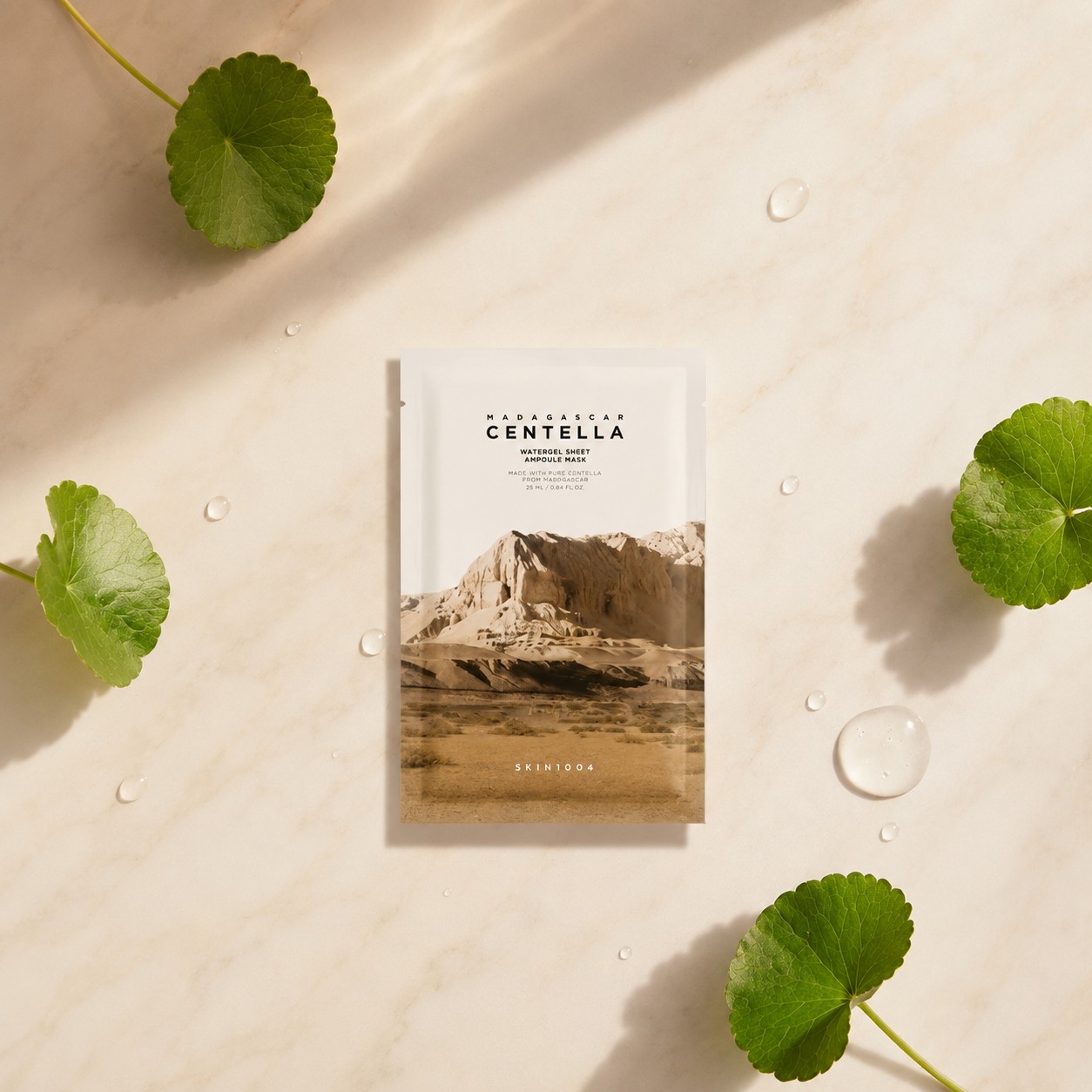 Masque SKIN1004 Madagascar Centella Watergel Sheet Ampoule Mask présenté sur fond clair avec feuilles de centella et gouttes d’eau.
