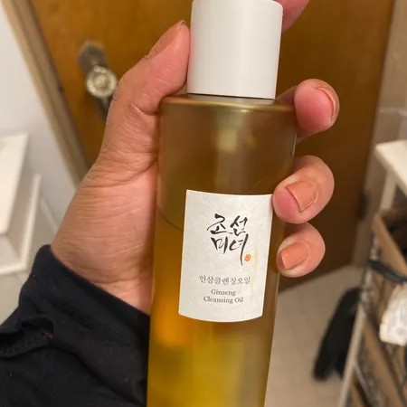 Beauty of Joseon Ginseng Cleansing Oil tenu en main dans une salle de bain.