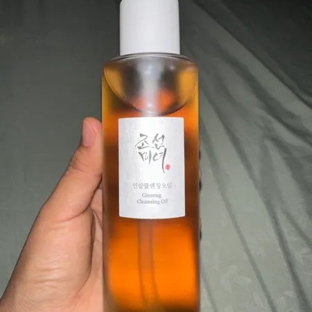 Beauty of Joseon Ginseng Cleansing Oil tenu en main, photographié de près avec son flacon ambré.