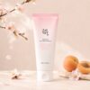 Beauty of Joseon Apricot Blossom Peeling Gel présenté avec fleurs d’abricotier et abricots sur fond crème.