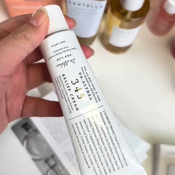 Dr. Althea 345 Relief Cream tenue en main devant une sélection de produits de soin.
