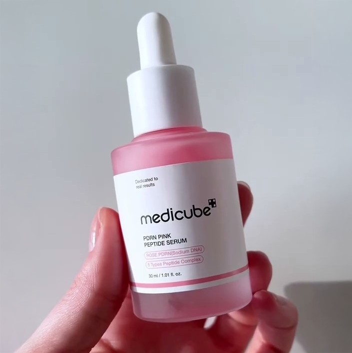 Gros plan du flacon rose Medicube PDRN Pink Peptide Serum tenu en main