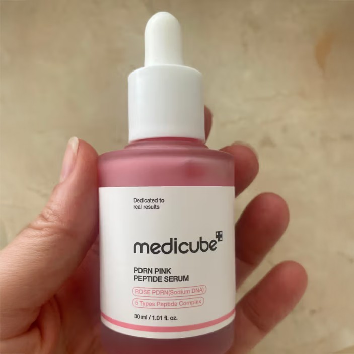 Gros plan du flacon Medicube PDRN Pink Peptide Serum tenu dans la main