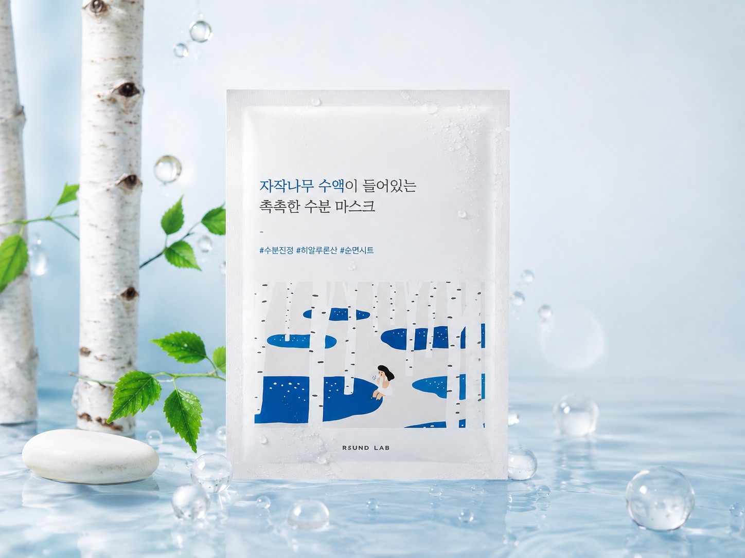 Masque hydratant ROUND LAB Silver Birch Juice présenté dans un décor frais avec bouleaux, eau et feuilles vertes.