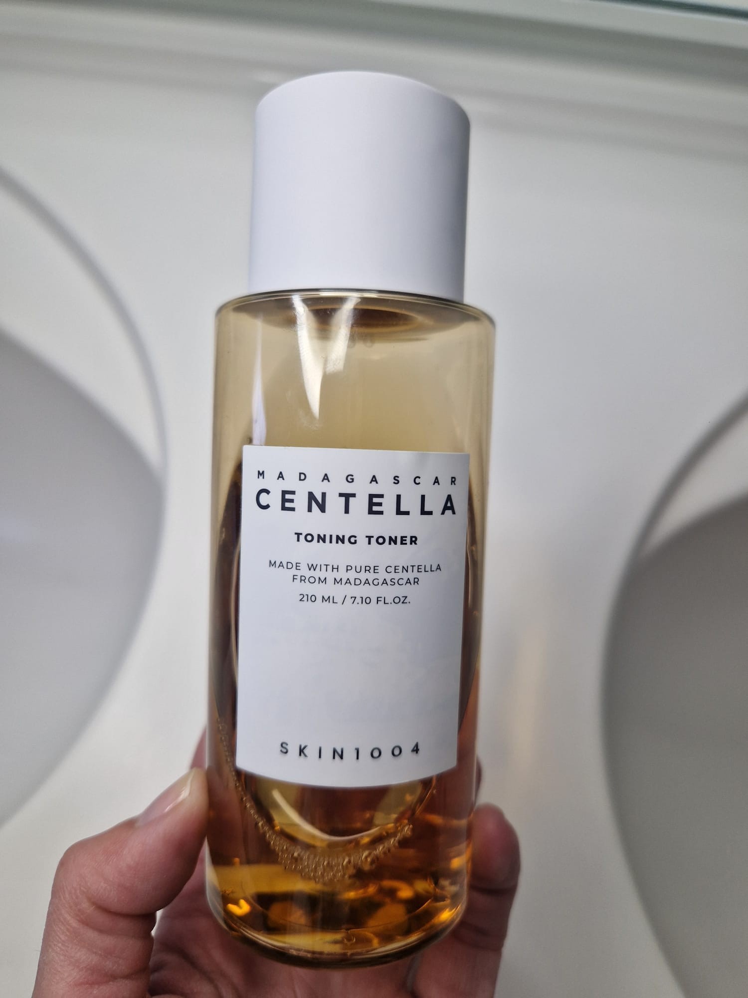 Flacon du SKIN1004 Madagascar Centella Toning Toner tenu en main devant un fond clair.