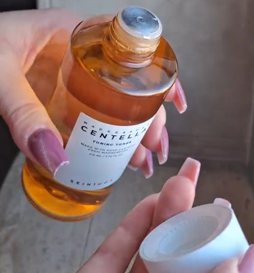 Flacon ouvert du SKIN1004 Madagascar Centella Toning Toner avec son bouchon tenu en main.