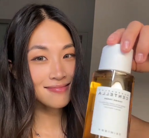 Femme présentant le flacon SKIN1004 Madagascar Centella Toning Toner face à la caméra.