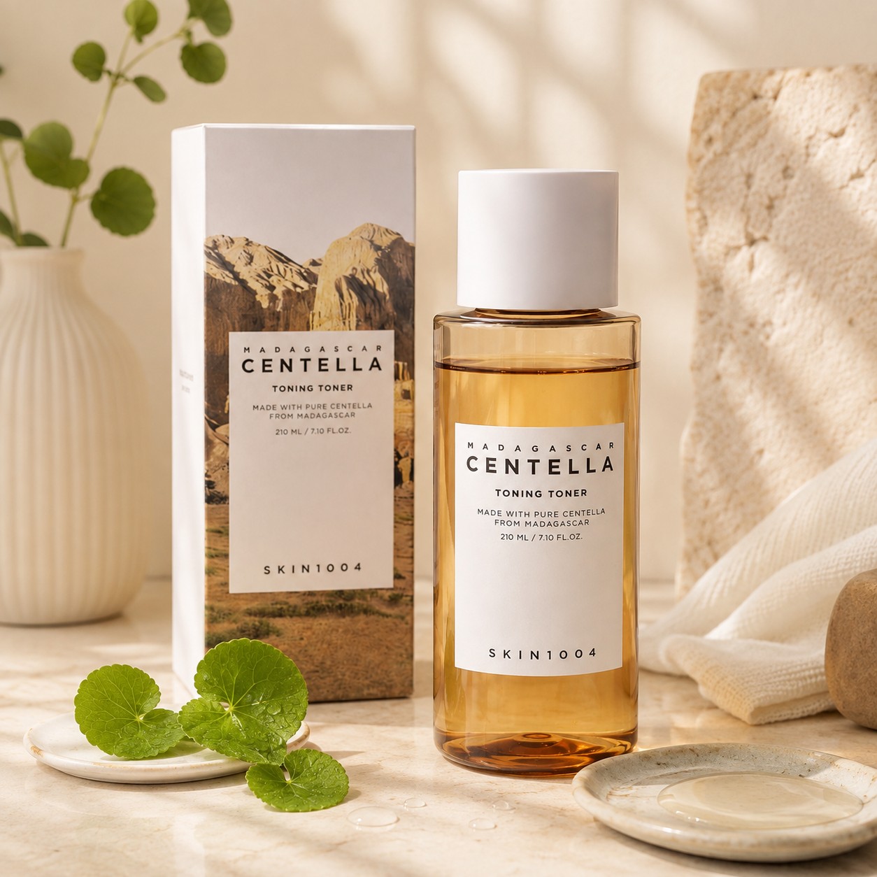 SKIN1004 Madagascar Centella Toning Toner et sa boîte dans une mise en scène crème avec feuilles de centella.