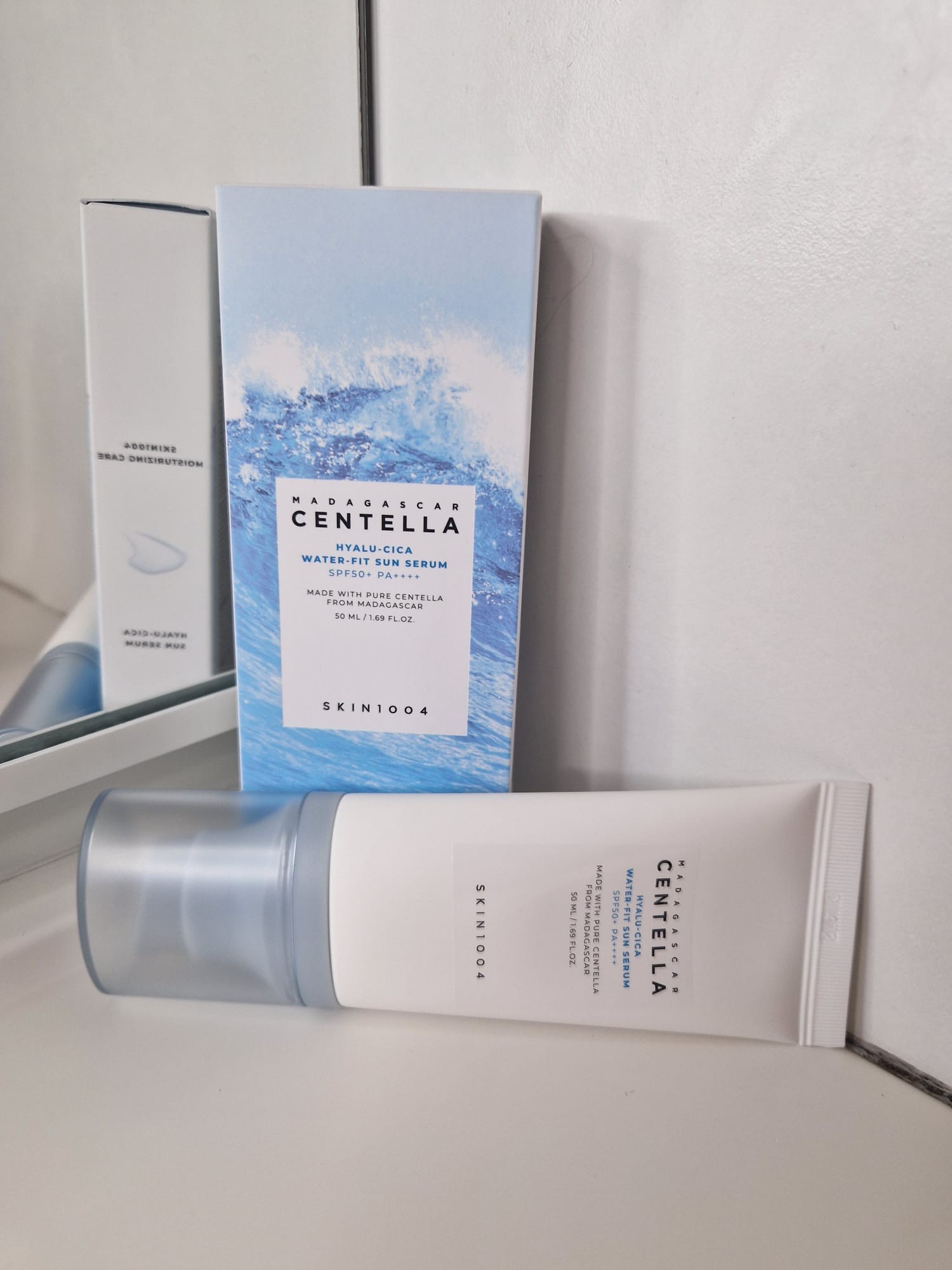 Boîte et tube du SKIN1004 Hyalu-Cica Water-Fit Sun Serum SPF50+, le tube étant posé à l’horizontale près d’un miroir.