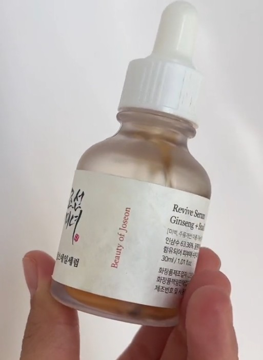 Flacon du Revive Serum Ginseng + Snail Mucin de Beauty of Joseon tenu en main, avec pipette blanche.