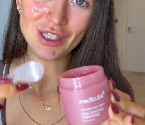 Utilisatrice appliquant la Medicube Collagen Jelly Cream sur sa joue près du pot ouvert