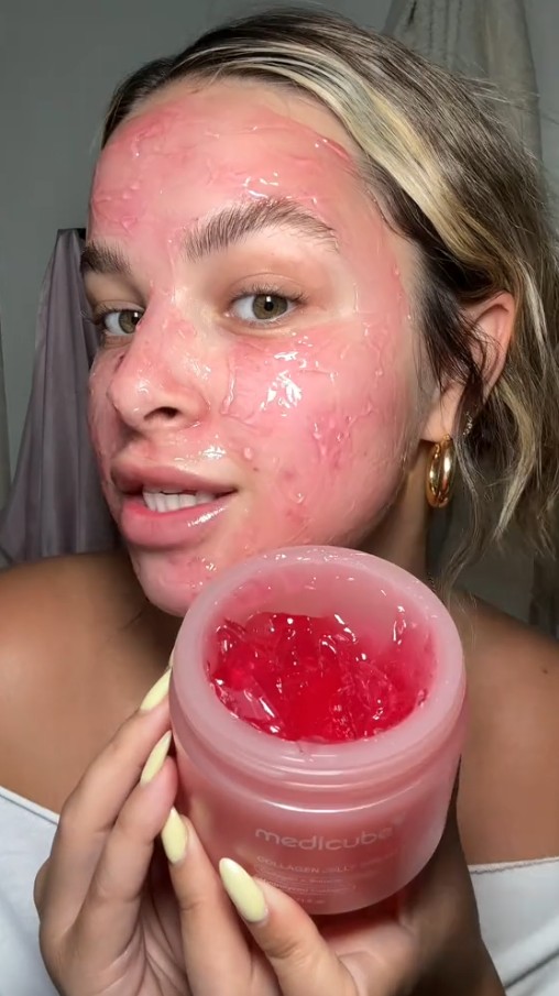 Utilisatrice avec la gelée rose appliquée sur le visage, tenant le pot ouvert de Medicube Collagen Jelly Cream
