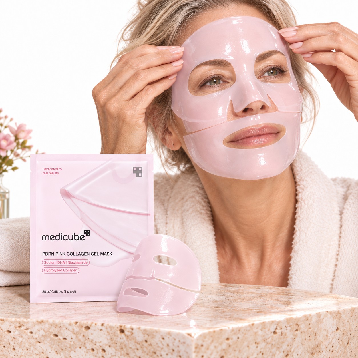 Femme appliquant le Medicube PDRN Pink Collagen Gel Mask en deux parties, avec le sachet du produit.