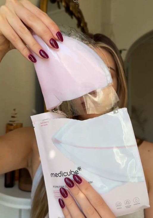 Femme retirant le masque hydrogel rose de son sachet Medicube avant l’application.