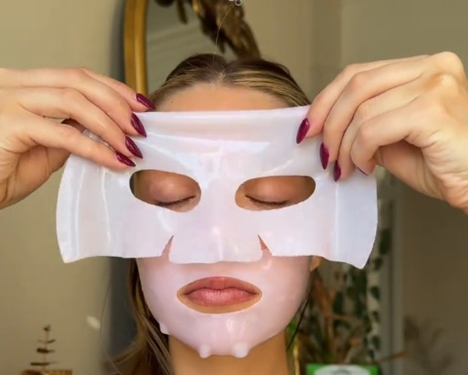 Femme positionnant la partie supérieure d’un masque hydrogel rose autour des yeux.