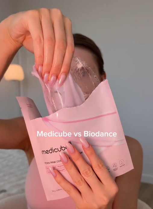 Femme tenant le sachet rose du Medicube PDRN Pink Collagen Gel Mask.