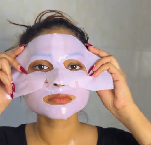 Femme ajustant les deux parties du Medicube PDRN Pink Collagen Gel Mask sur son visage.