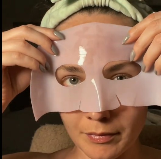 Femme positionnant la partie supérieure du masque hydrogel rose sur le front et le contour des yeux.