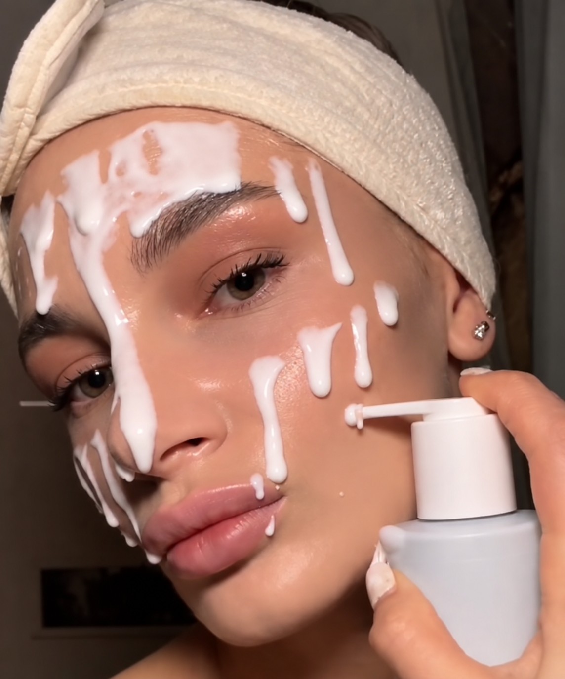 Femme appliquant le lait nettoyant SKIN1004 Gentle Cleansing Milk en lignes crémeuses sur son visage