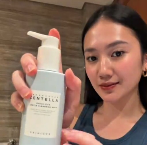 Femme présentant face caméra le flacon pompe bleu du SKIN1004 Gentle Cleansing Milk