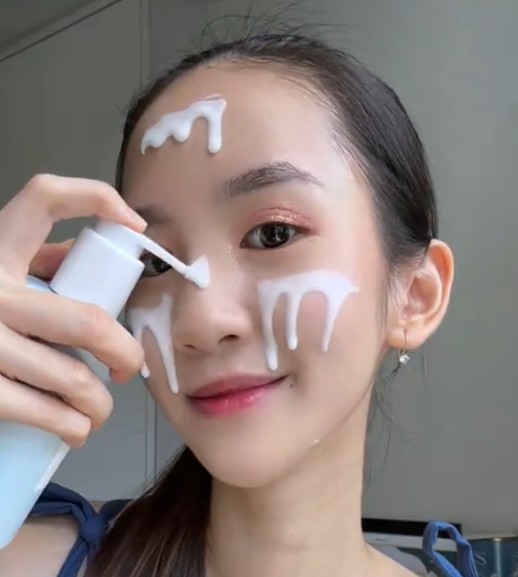 Femme déposant le SKIN1004 Gentle Cleansing Milk sur son front et ses joues avec la pompe