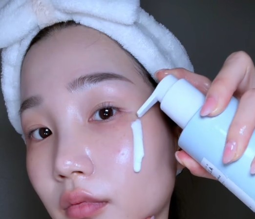 Femme avec un bandeau appliquant le SKIN1004 Gentle Cleansing Milk directement sur sa joue