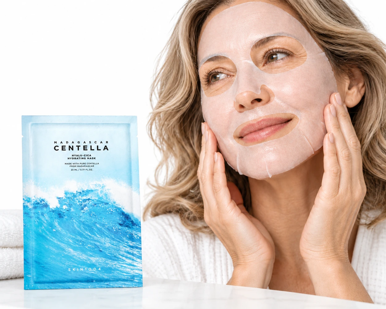 Femme à la peau mature portant le masque tissu SKIN1004 Hyalu-Cica près de son sachet