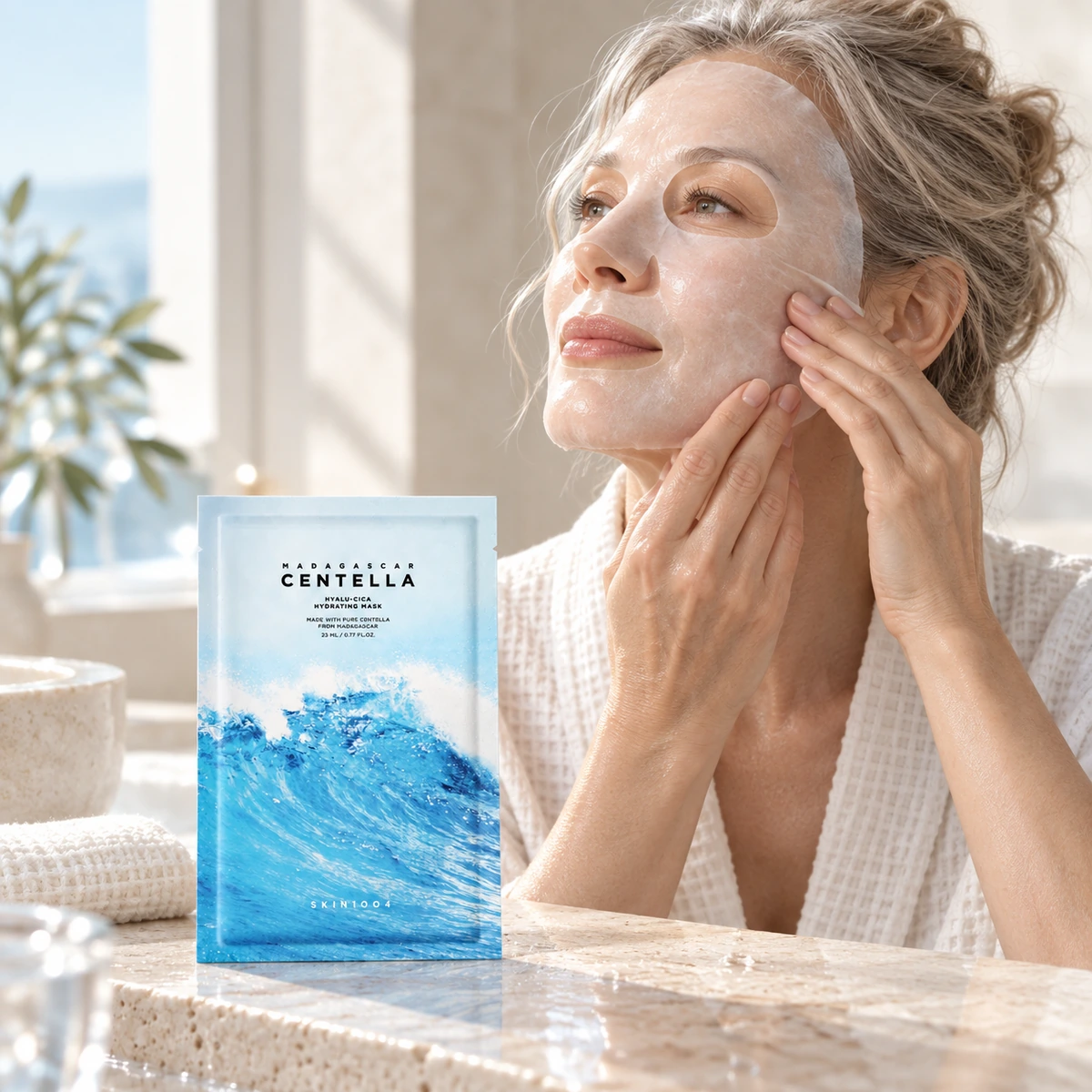 Femme à la peau mature ajustant un masque tissu près du sachet SKIN1004 Hyalu-Cica Hydrating Mask