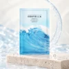Sachet bleu du masque tissu SKIN1004 Hyalu-Cica Hydrating Mask posé sur un socle en pierre claire avec des reflets d’eau