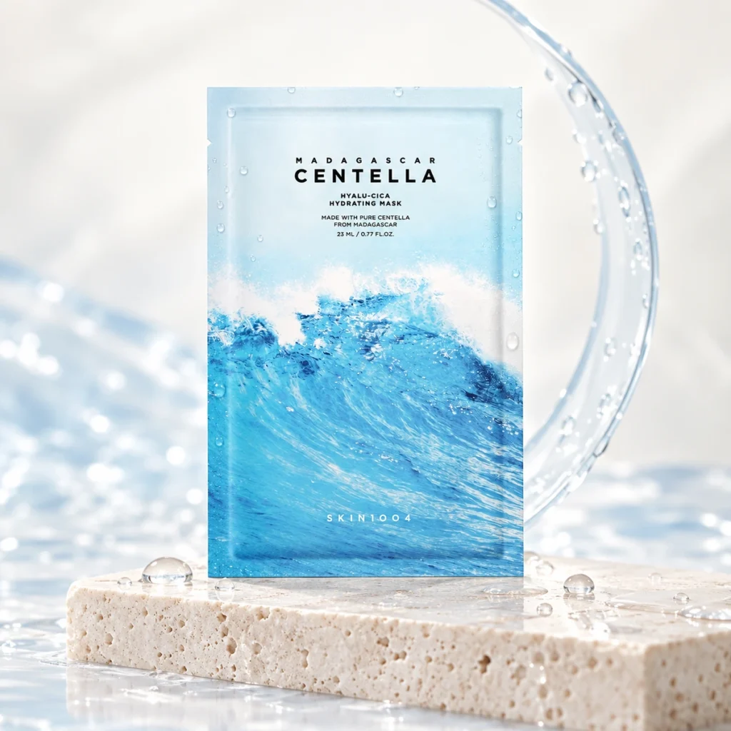 Sachet bleu du masque tissu SKIN1004 Hyalu-Cica Hydrating Mask posé sur un socle en pierre claire avec des reflets d’eau