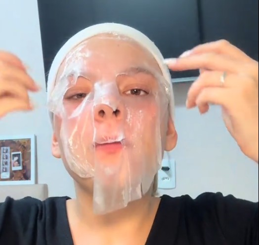 Utilisatrice portant le masque tissu SKIN1004 Hyalu-Cica et l’ajustant sur son front