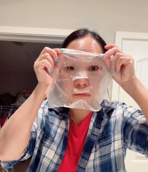 Utilisatrice tenant le masque tissu translucide déplié devant son visage