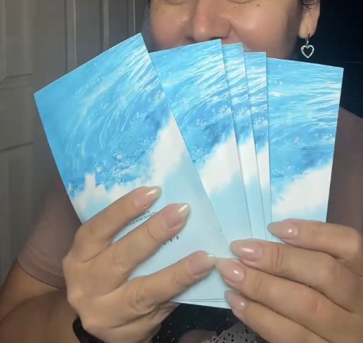 Utilisatrice souriante présentant plusieurs sachets du masque SKIN1004 Hyalu-Cica