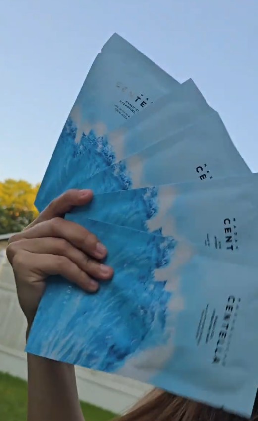 Main présentant plusieurs sachets bleus du masque SKIN1004 Hyalu-Cica en extérieur