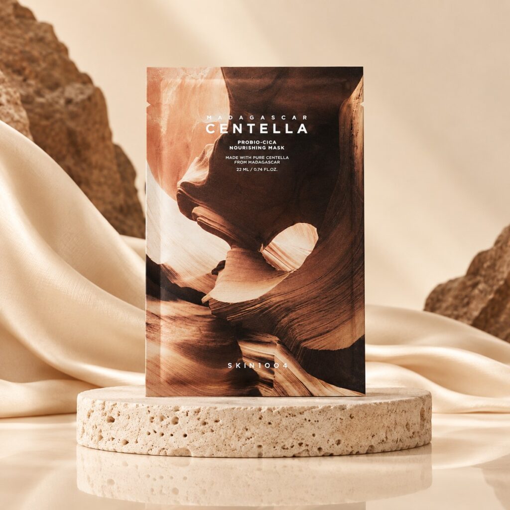 Sachet du masque tissu SKIN1004 Probio-Cica Nourishing Mask posé sur un socle clair dans un décor minéral beige et brun